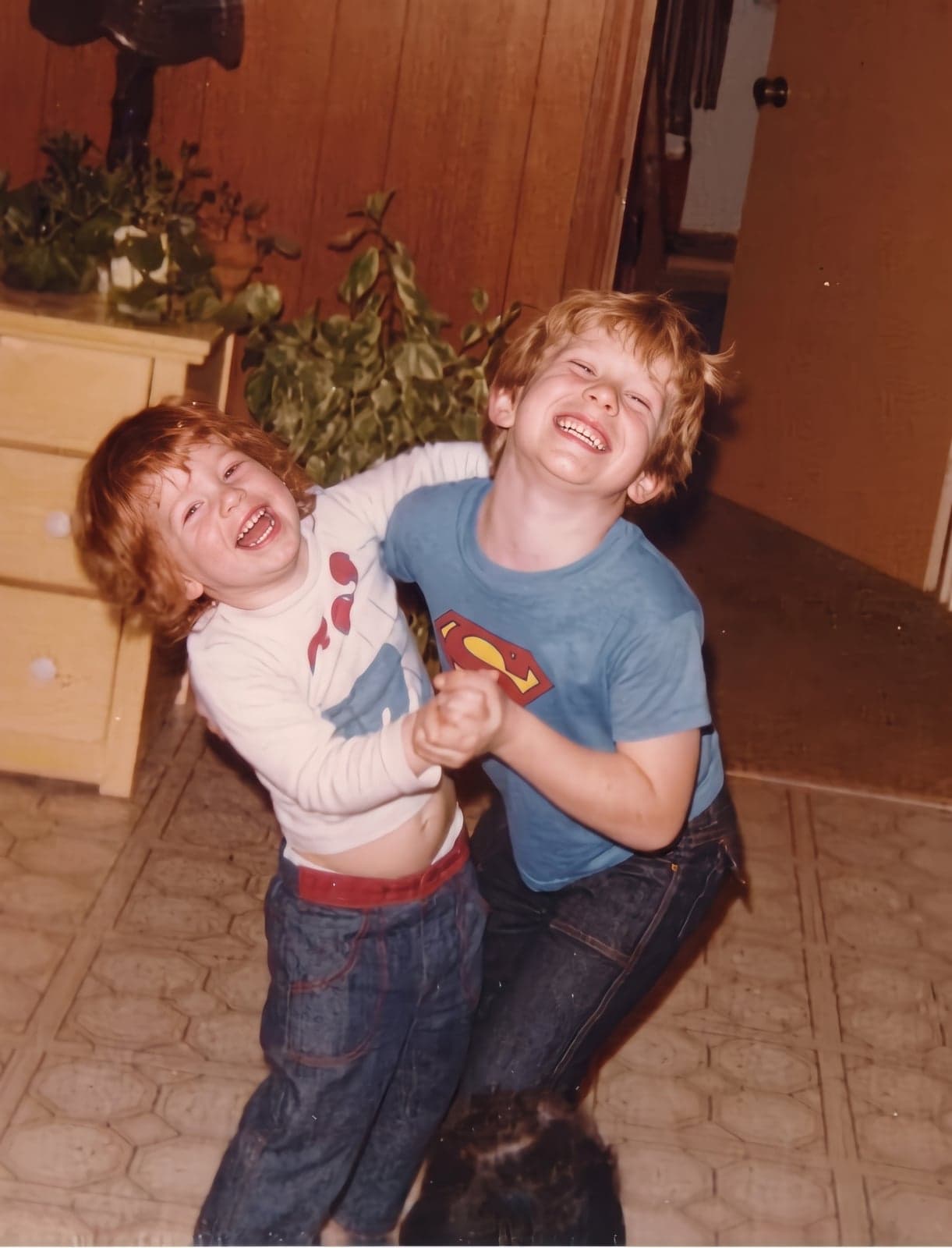 A 1970s snapshot of two laughing boys playing in a living room, upscaled