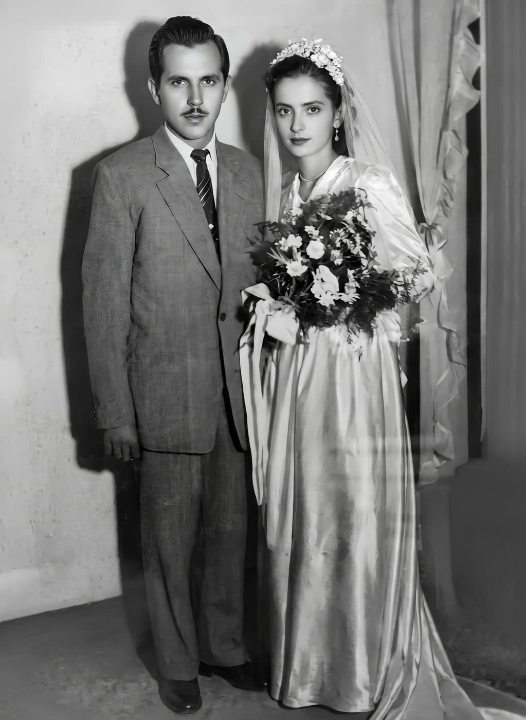 A faded 1940s wedding portrait of a bride with a bouquet and a groom in a suit, restored