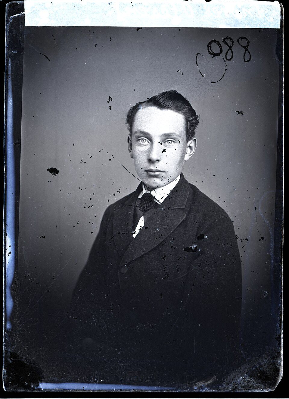 A spotted and stained studio portrait of a young man in a dark suit, before restoration