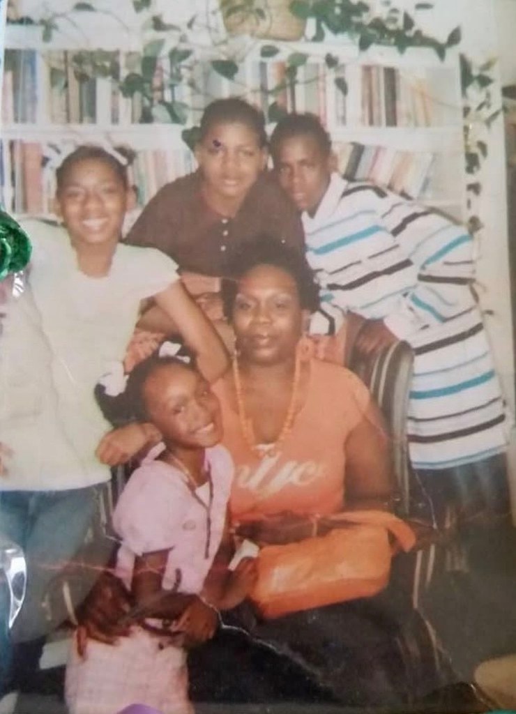 A phone photo of a printed family portrait, with glare and soft focus, before upscaling
