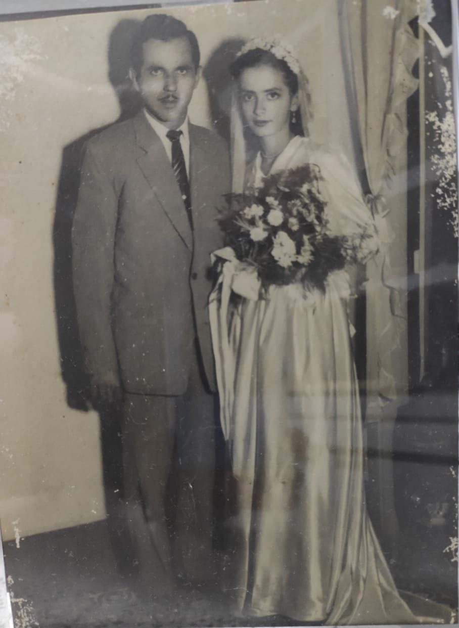 A faded 1940s wedding portrait of a bride with a bouquet and a groom in a suit, before restoration